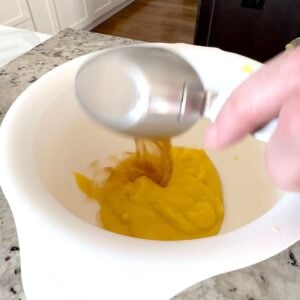 Mixing chicken broth and cream of chicken soup in a white bowl.