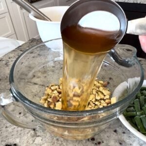 Mixing the dry stuffing and broth in a clear mixing bowl.