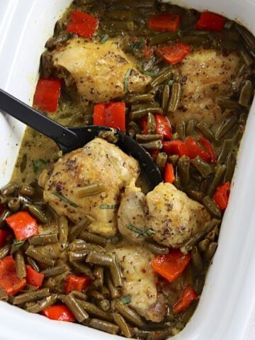 Thai basil chicken in slow cooker with a spoon.