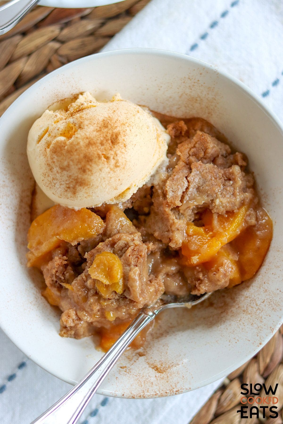 Crock pot peach cobbler with a scoop of ice cream.