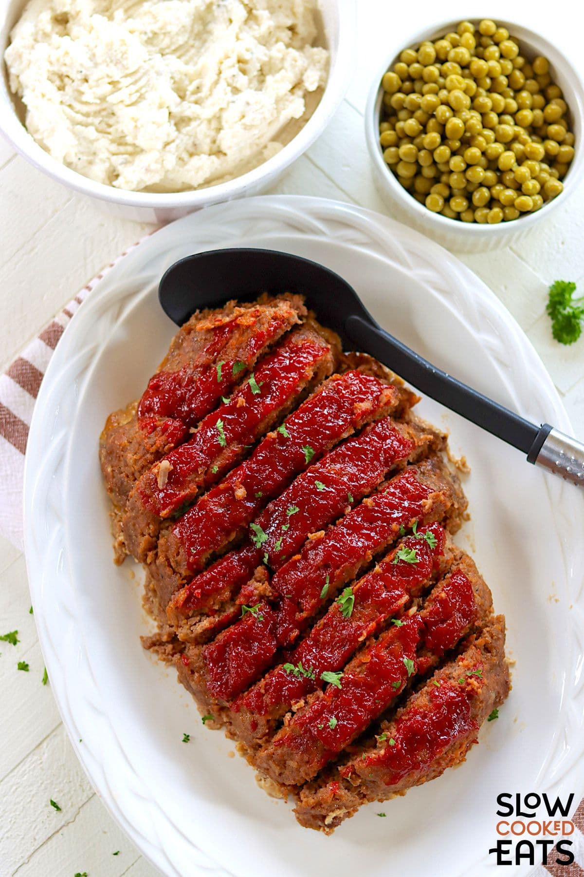 Meatloaf served alongside mashed potatoes and peas.