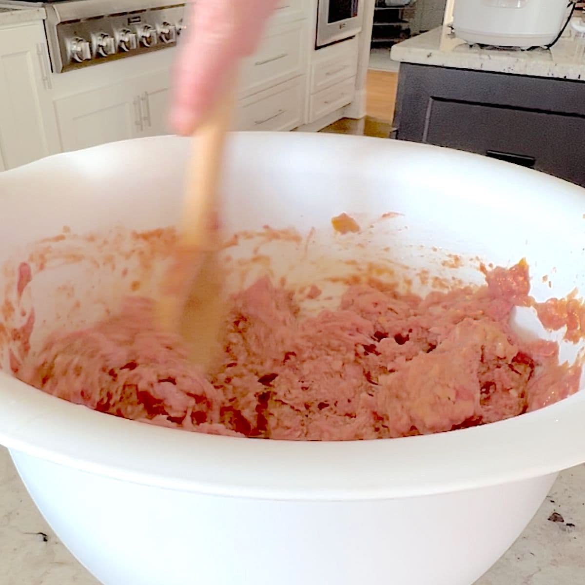 Mixing the meat loaf mixture in a white bowl.
