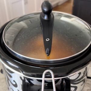 Slow cooking souther pulled chicken in a black and silver crock pot.