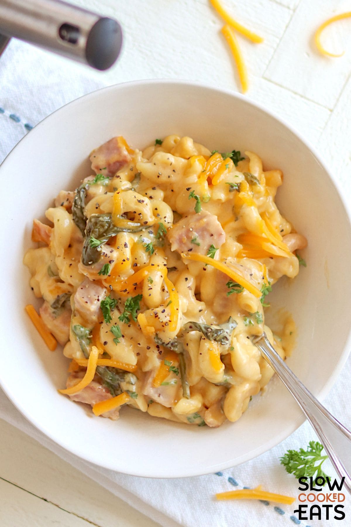 Crock pot macaroni ham and cheese casserole served with a spoon.