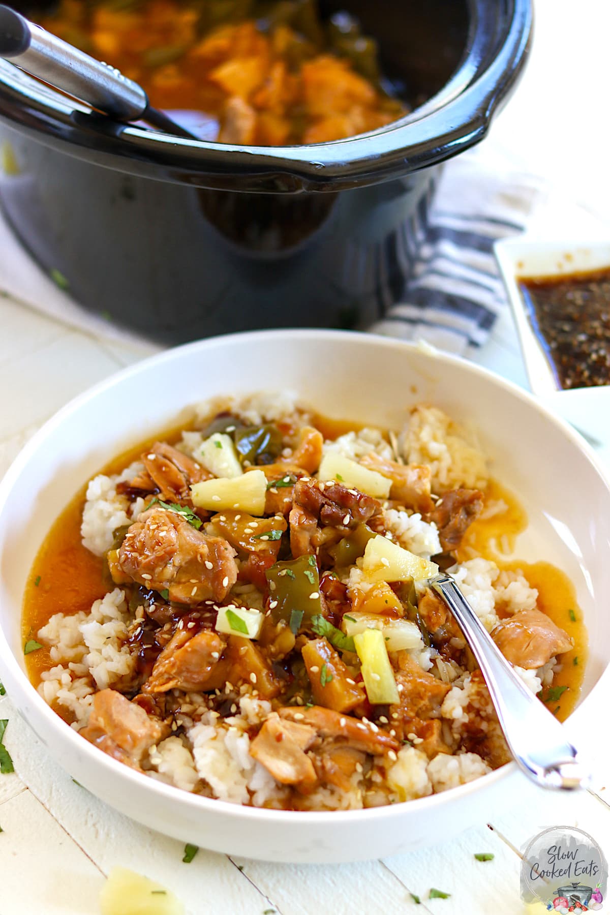 A white bowl of crock pot chicken teriyaki served over rice.