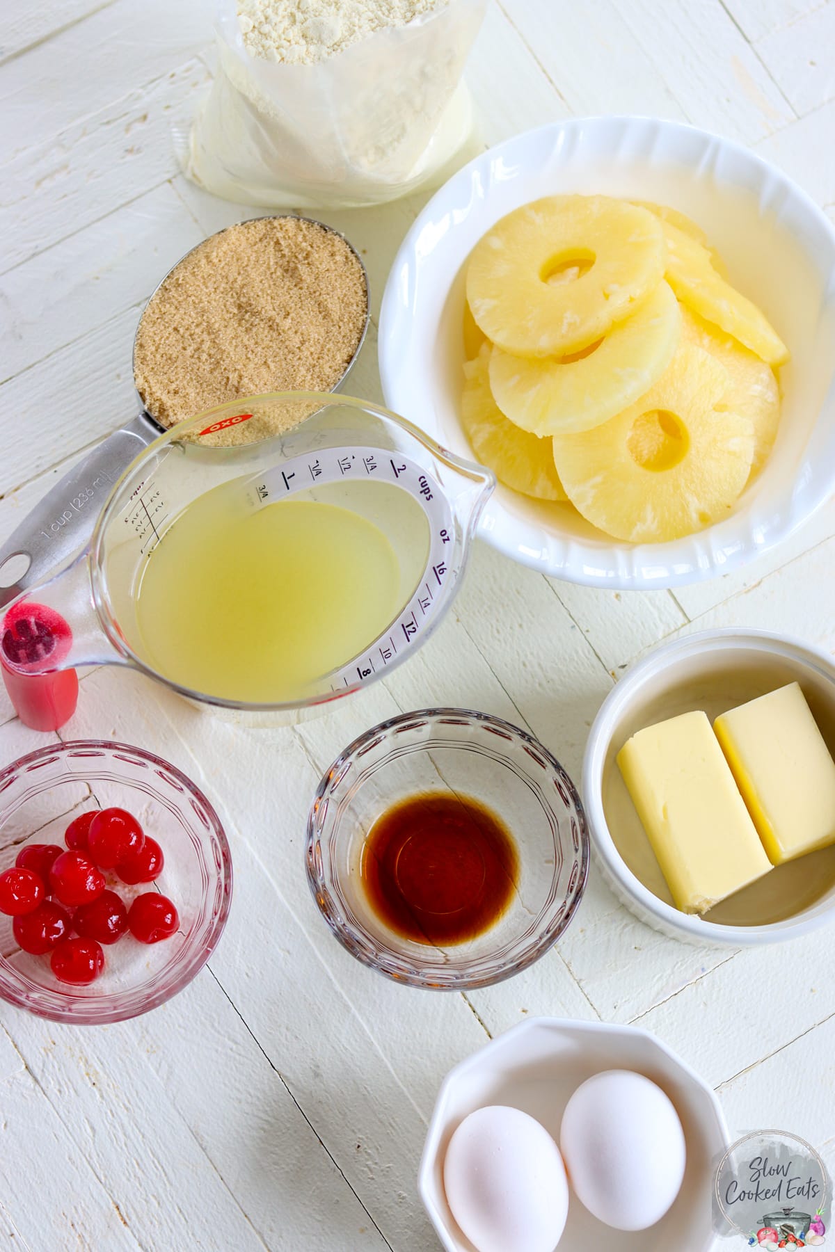 The ingredients needed for making crock pot pineapple upside down cake on a white board.