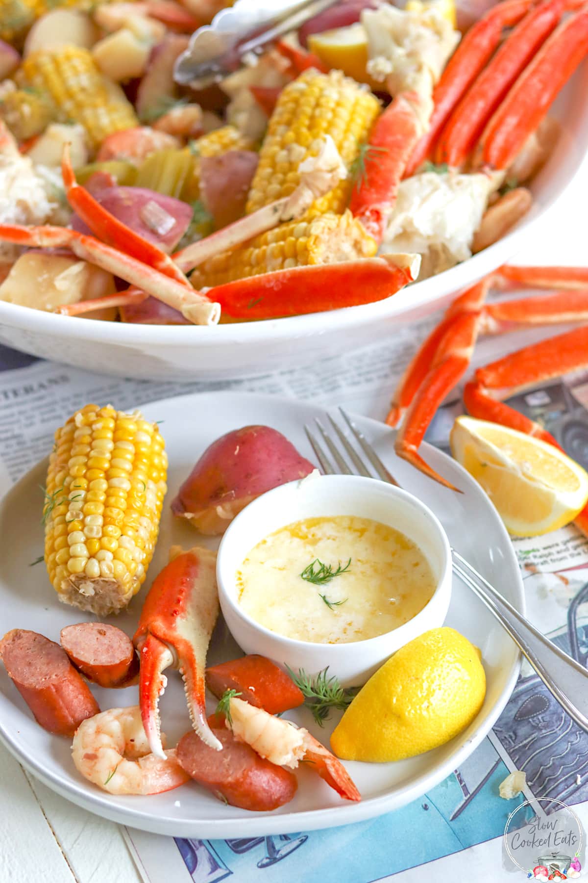 Crock pot seafood boil served on a white plate with corn, potatoes, andouille, shrimp, and crab.