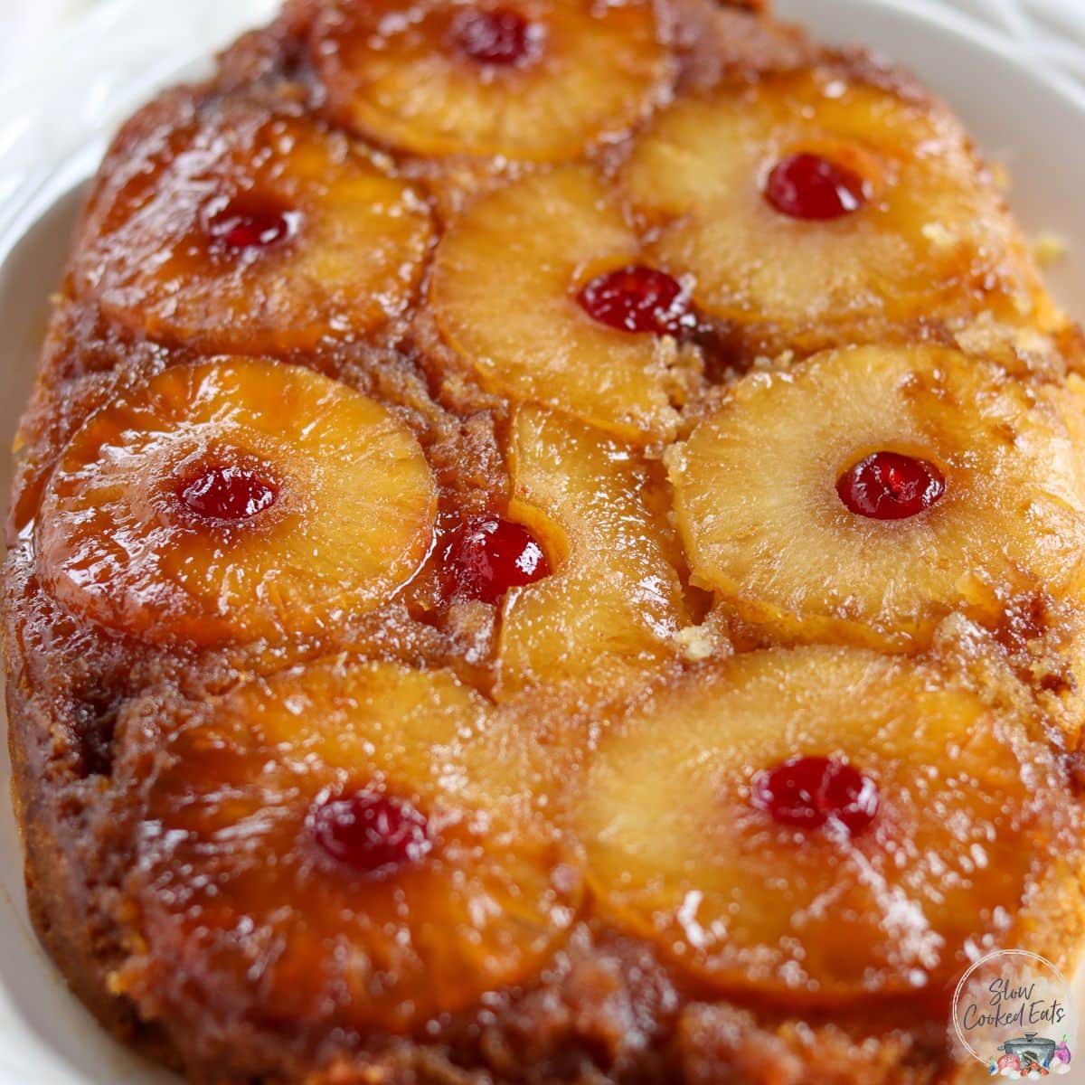 Pineapple upside down cake with slices of pineapple with maraschino cherries and a brown sugar butter glaze.