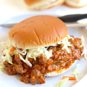 Crock pot sloppy joes served on a gray plate with coleslaw.