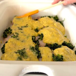 Spreading the sauce on top of the chicken and spinach.