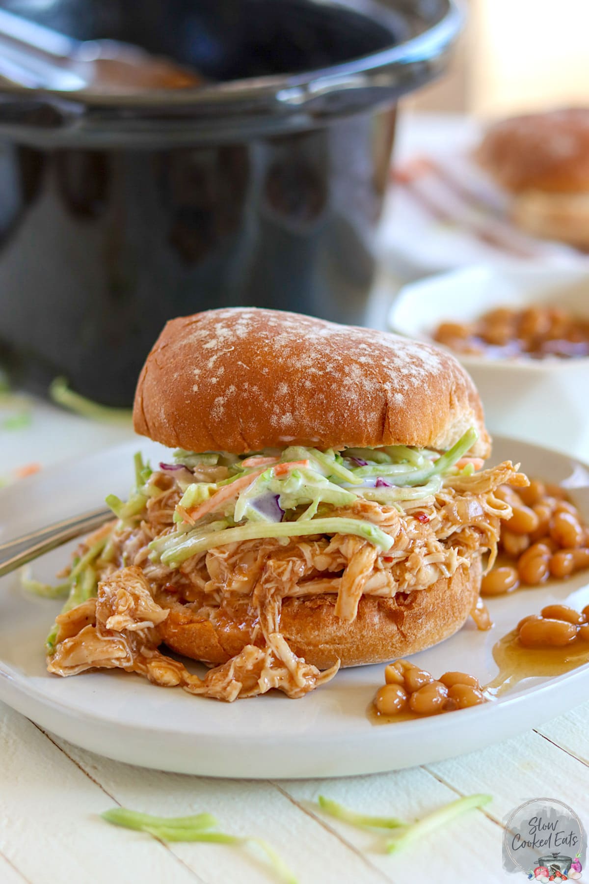 Crock pot pulled chicken on a hamburger bun with coleslaw.