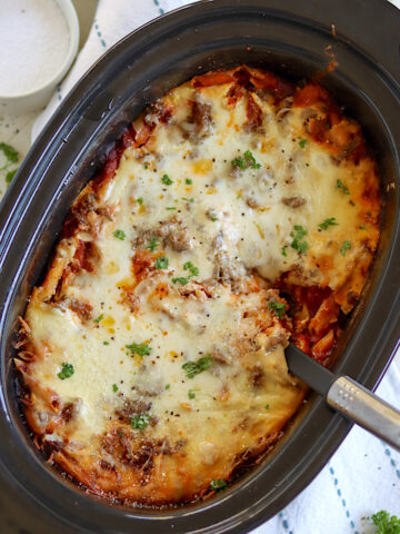 Baked ziti in a black oval slow cooker with handles.