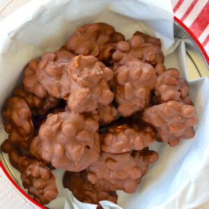 Chocolate peanut clusters piled up in a metal tin.