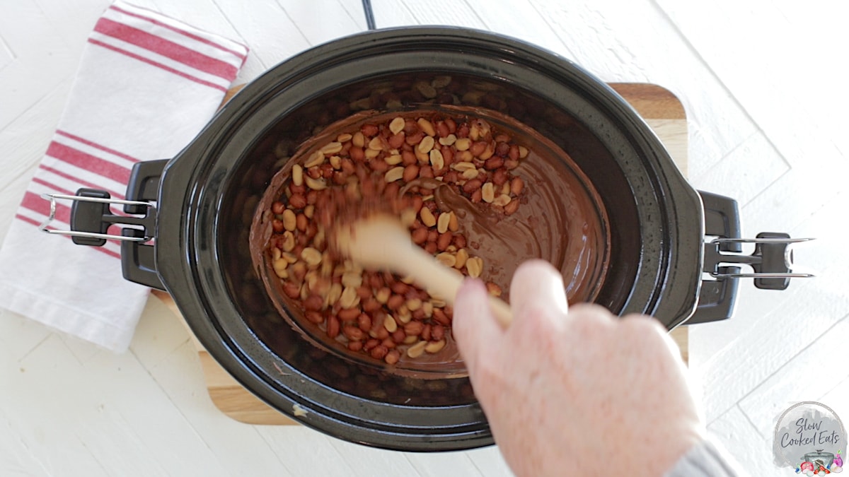 Stirring the added peanuts into the melted chocolate, butterscotch, and peanut butter.