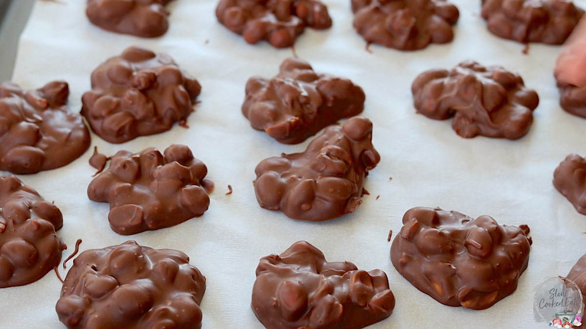 Finished crock pot peanut clusters on a tray of parchment paper.