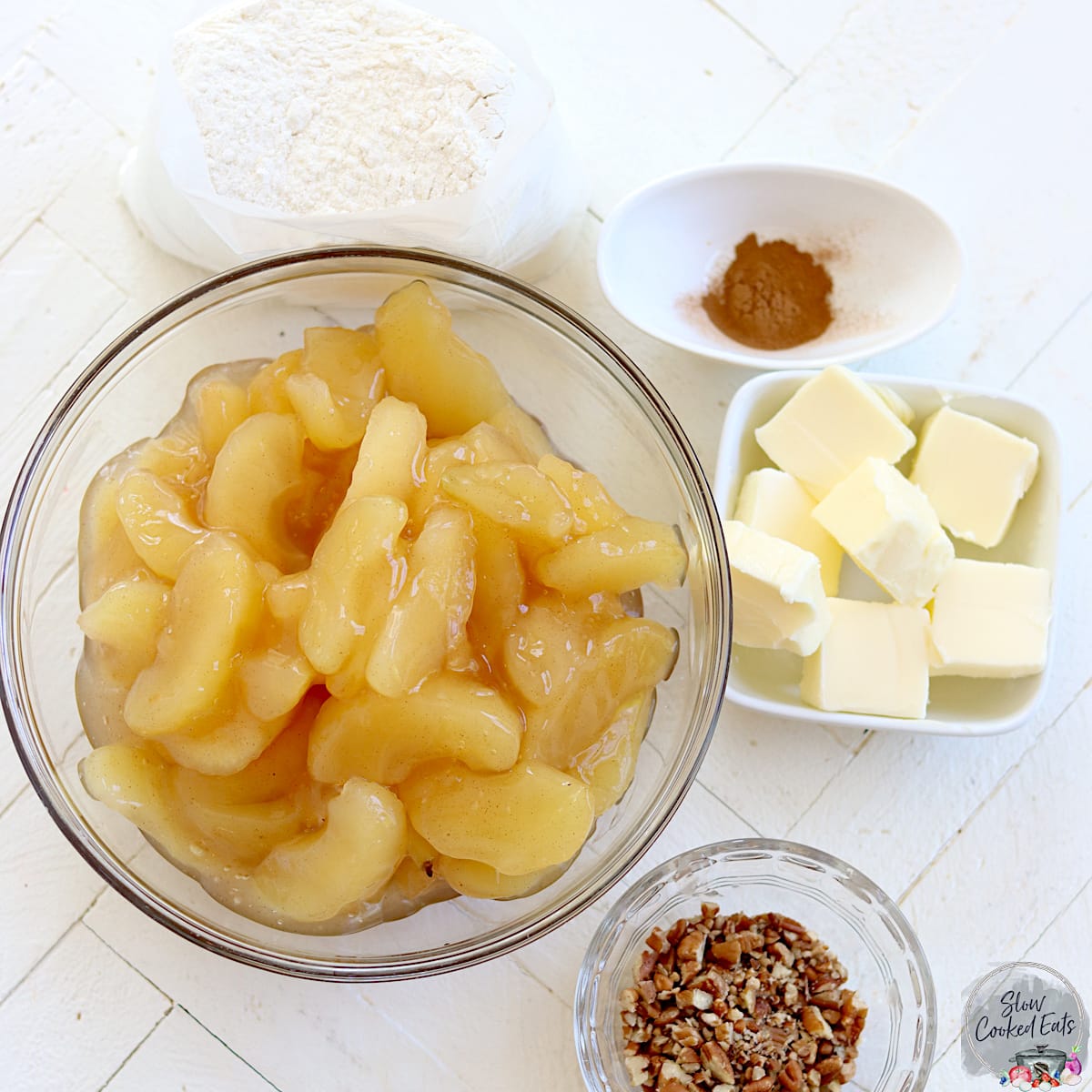 Ingredients needed for making crock pot apple crisp on a white wood board.