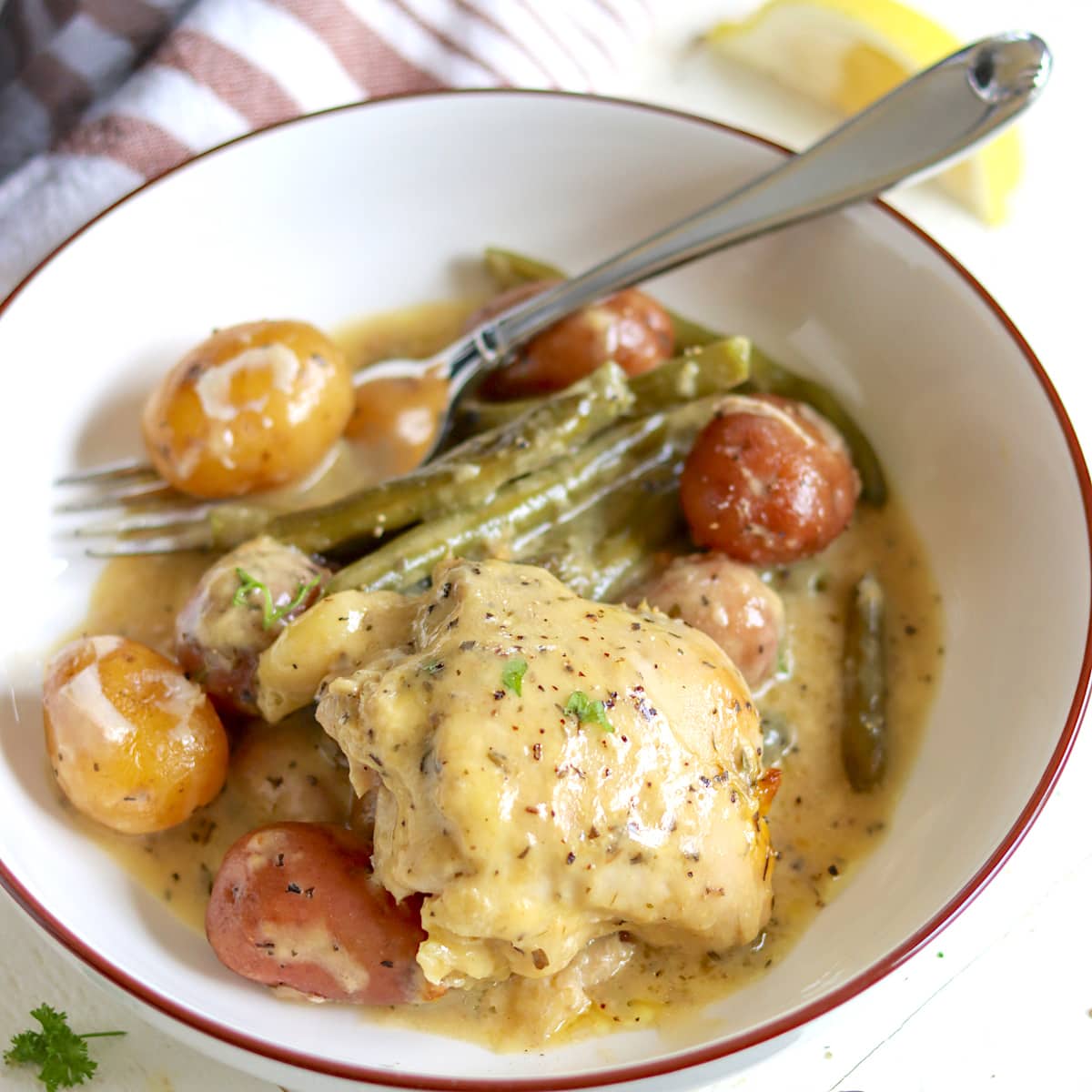 Chicken, potatoes, and green beans in a round white bowl with a brown rim.