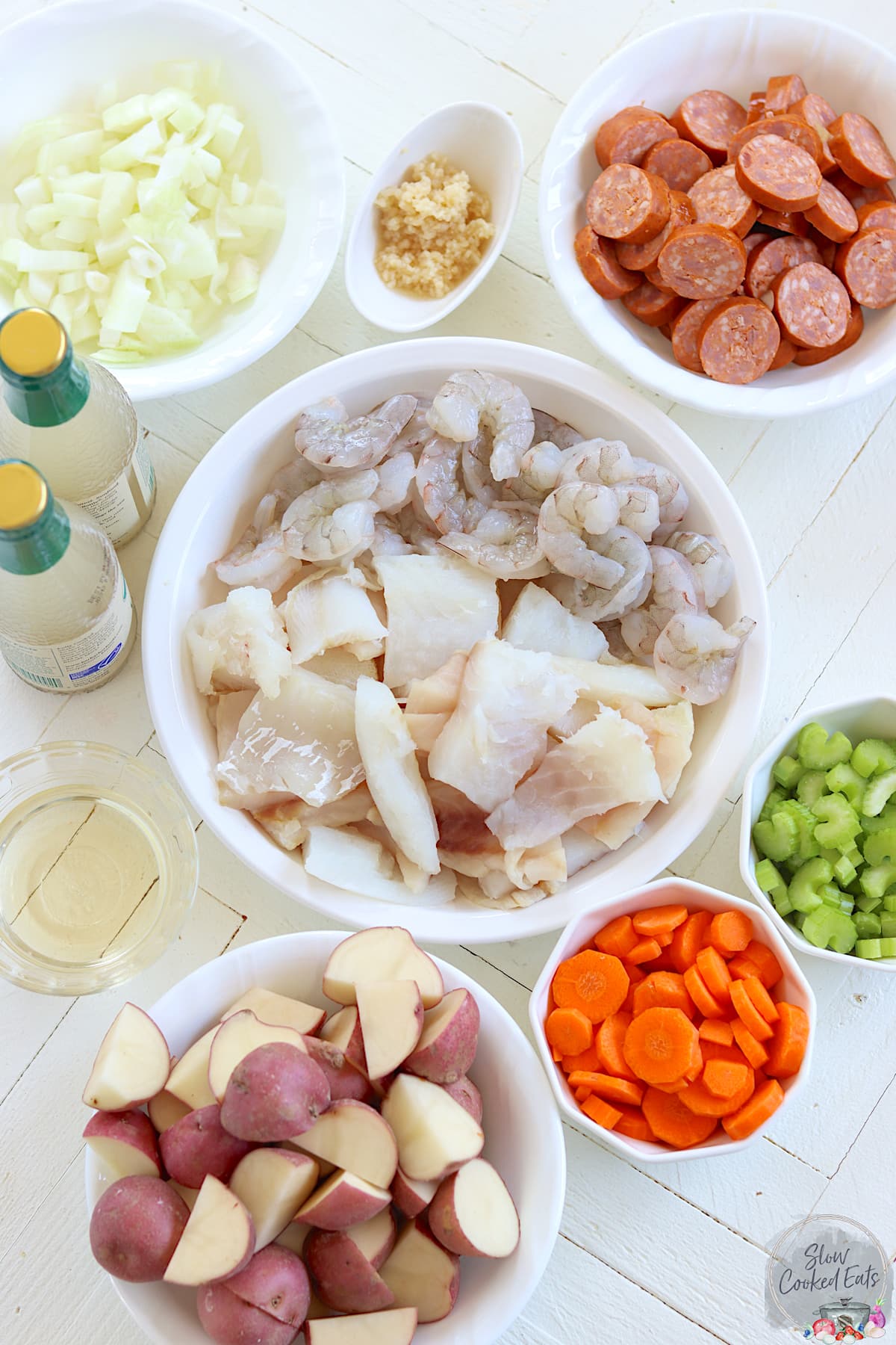 The ingredients needed for making crockpot seafood stew on a white board.