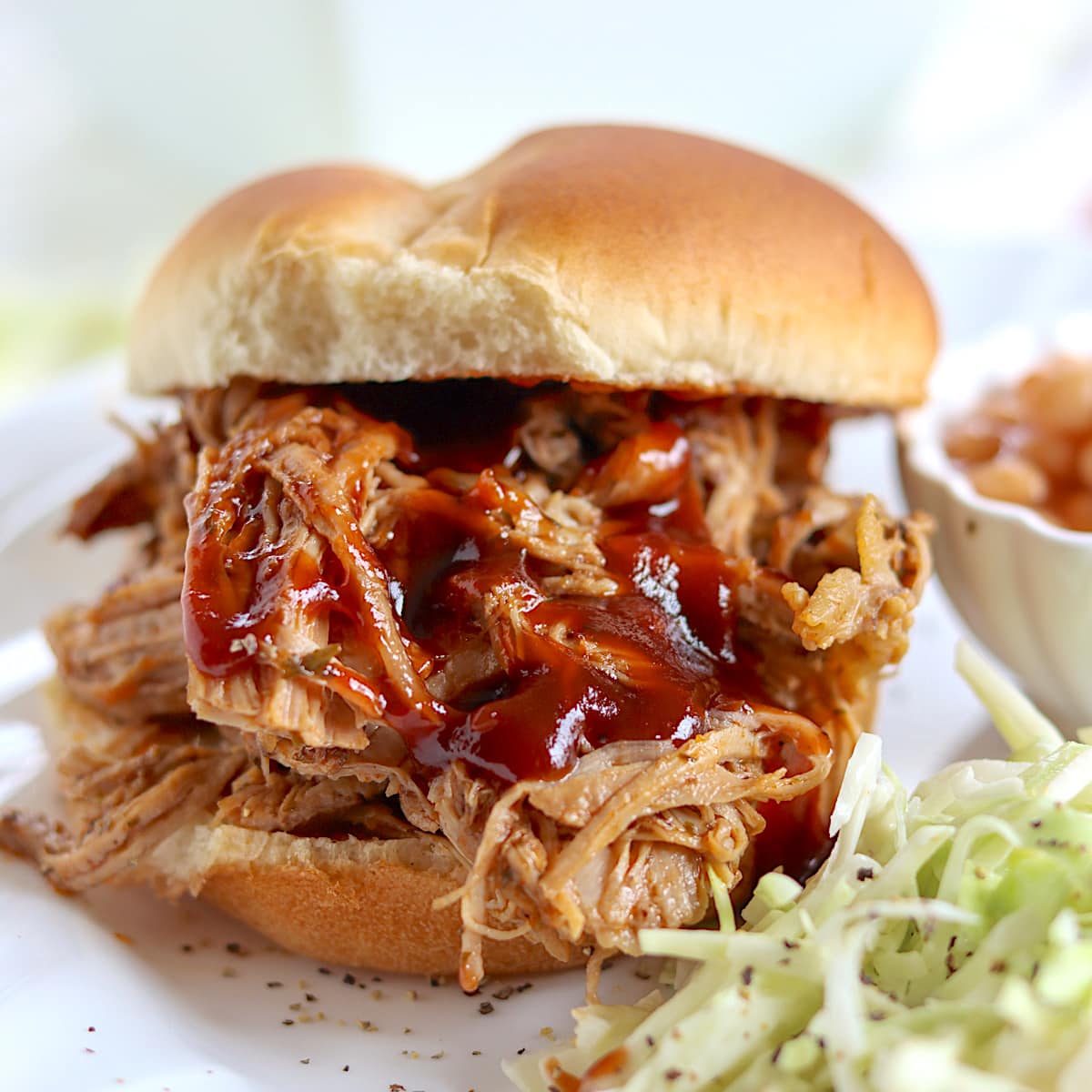 Juicy tender pulled pork slathered with barbecue sauce on a hamburger bun.