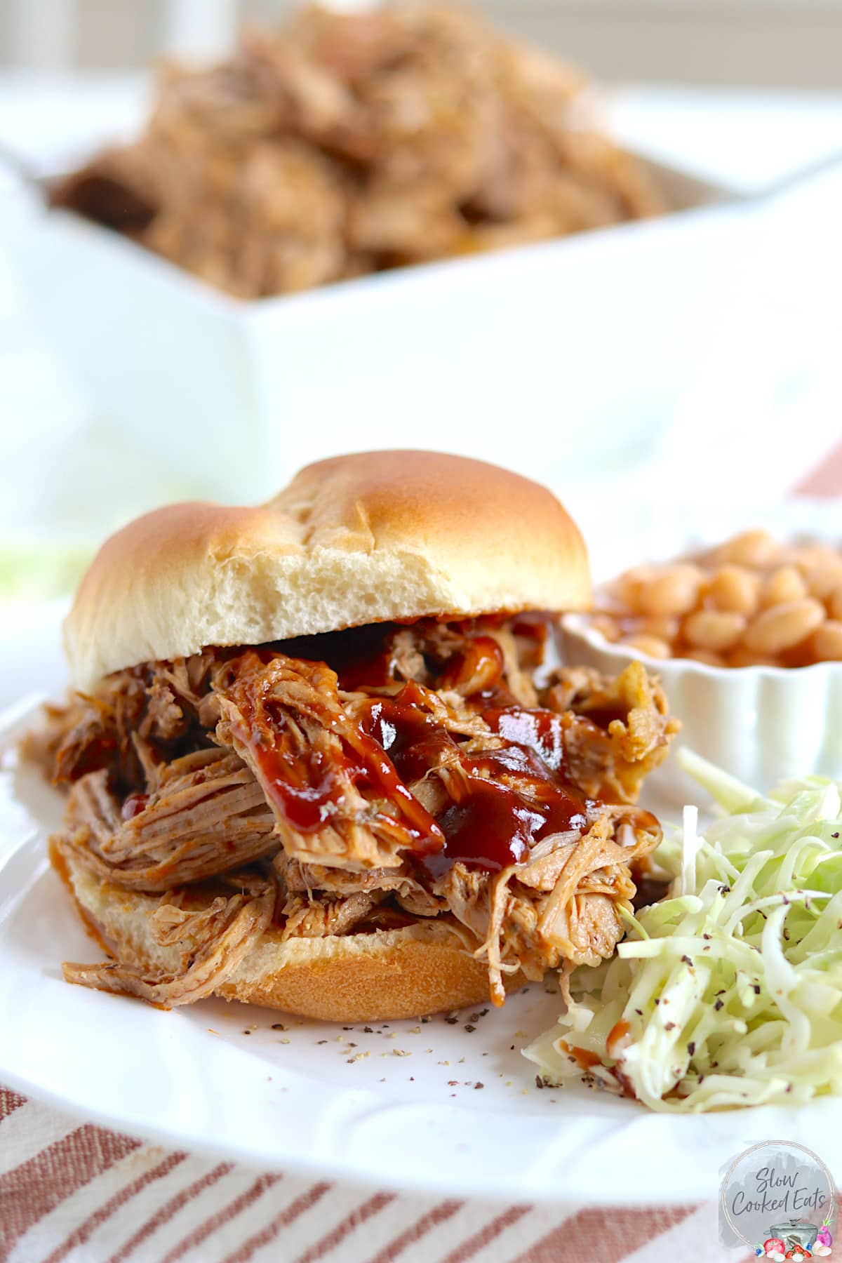 Dr. Pepper pulled pork served on a hamburger bun with bbq sauce, coleslaw, and baked beans.