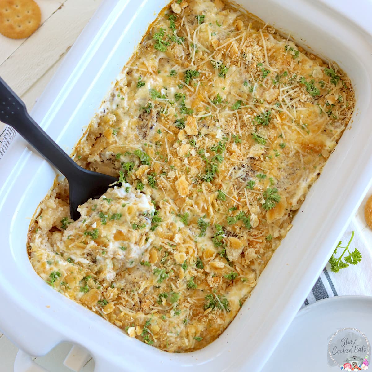 A white rectangle crock pot with ritz chicken garnished with parsley.