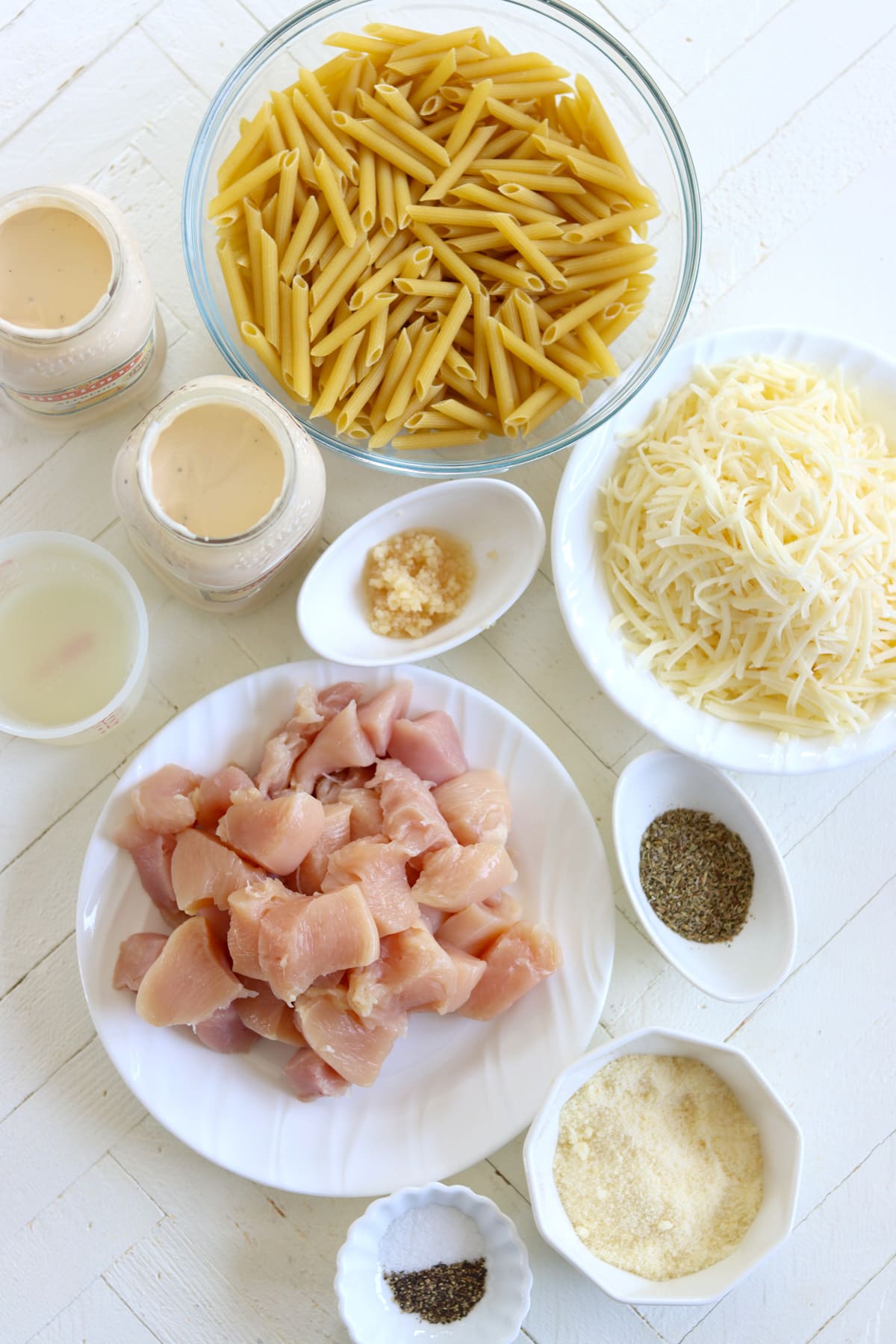 Ingredients needed for making crock pot chicken alfredo on a white board.