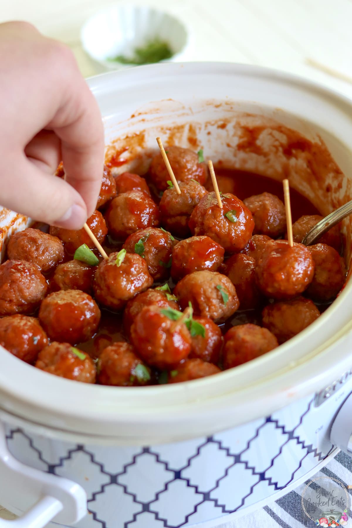 Grape jelly meatballs in a slow cooker with toothpicks.