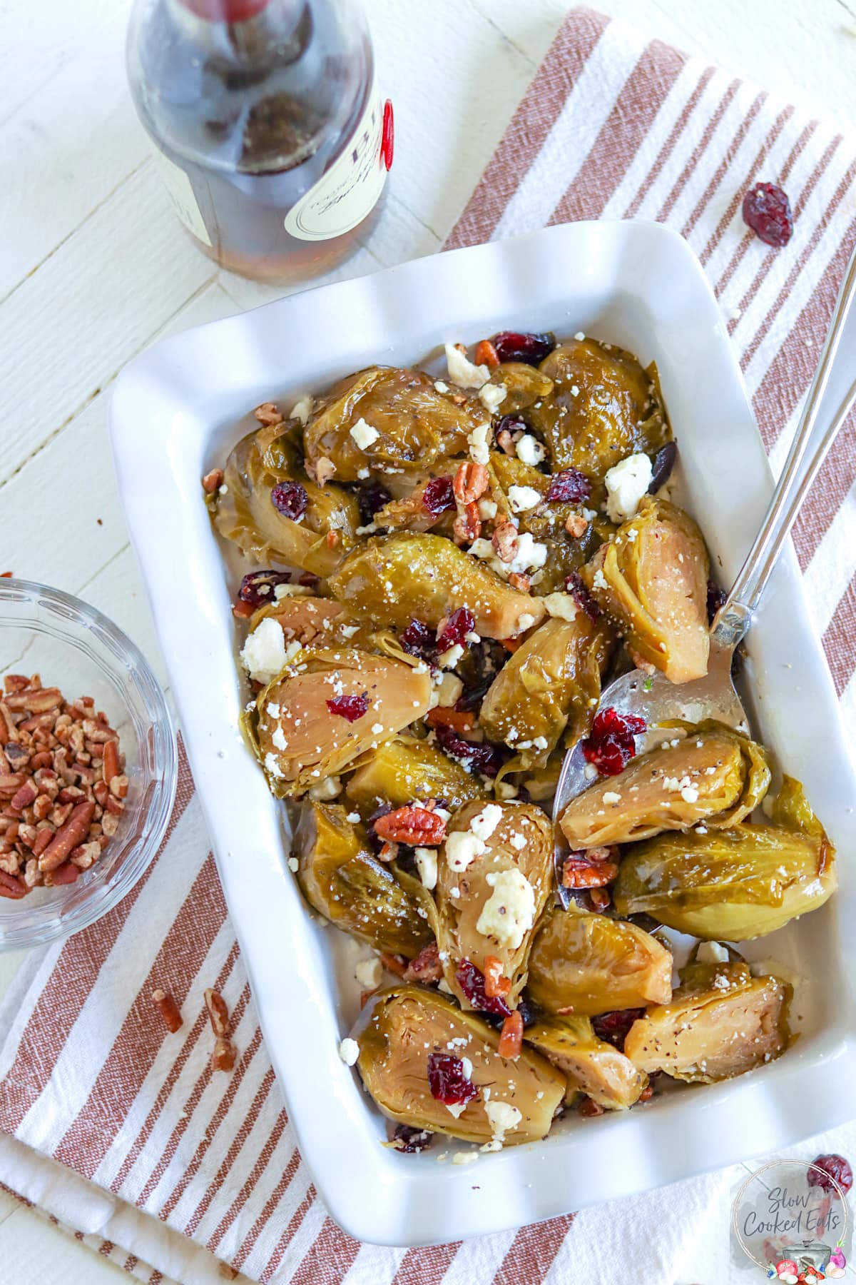 A fluted white rectangle dish of crockpot brussel sprouts with cranberries