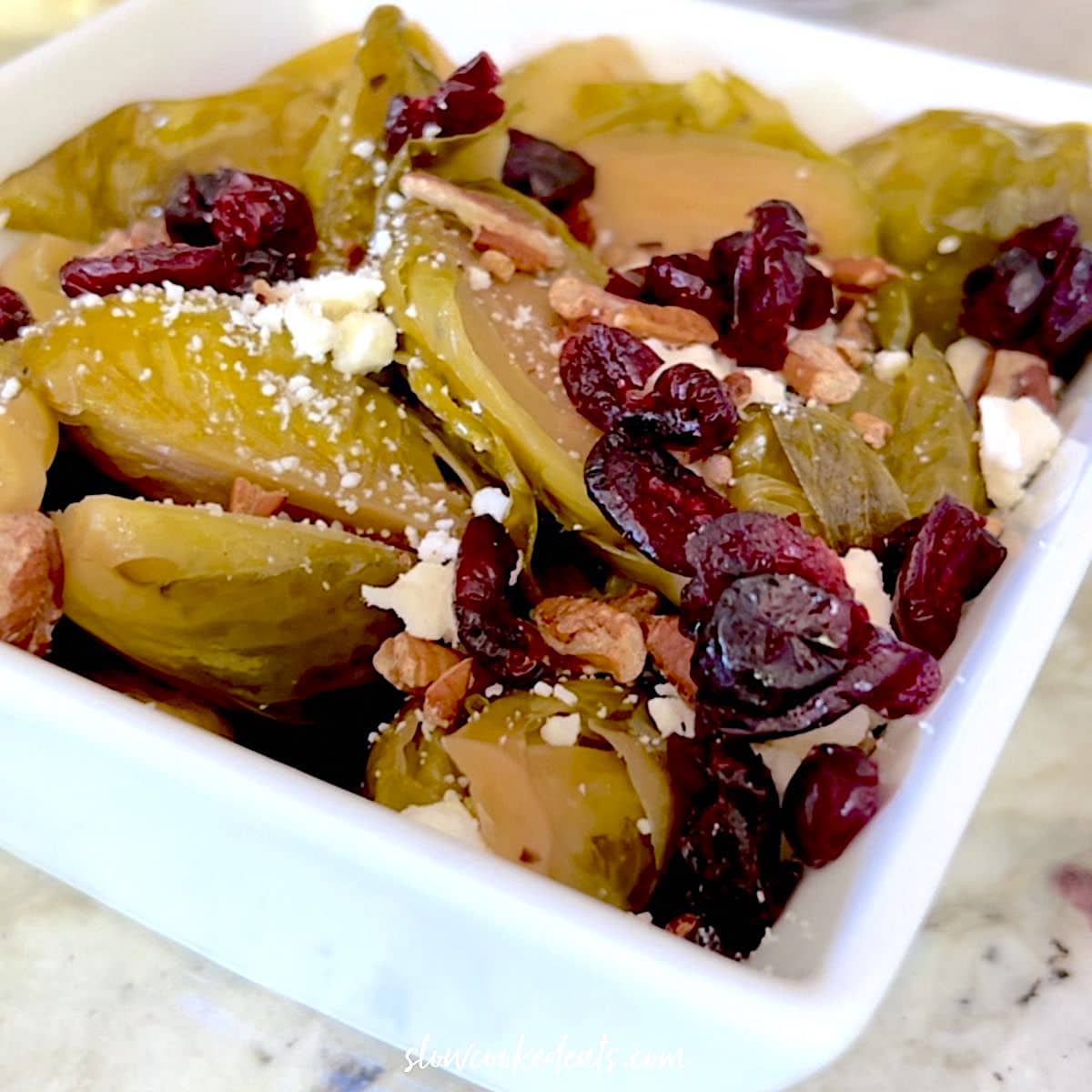 Topping brussel sprouts with cranberries, goat cheese, and walnuts.