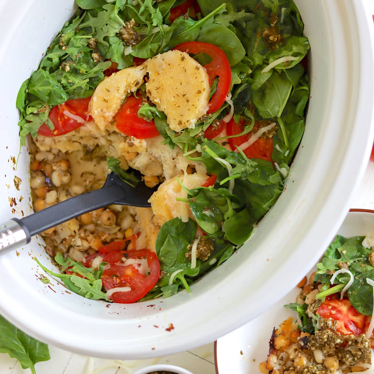 An oval white crock pot with vegetable casserole