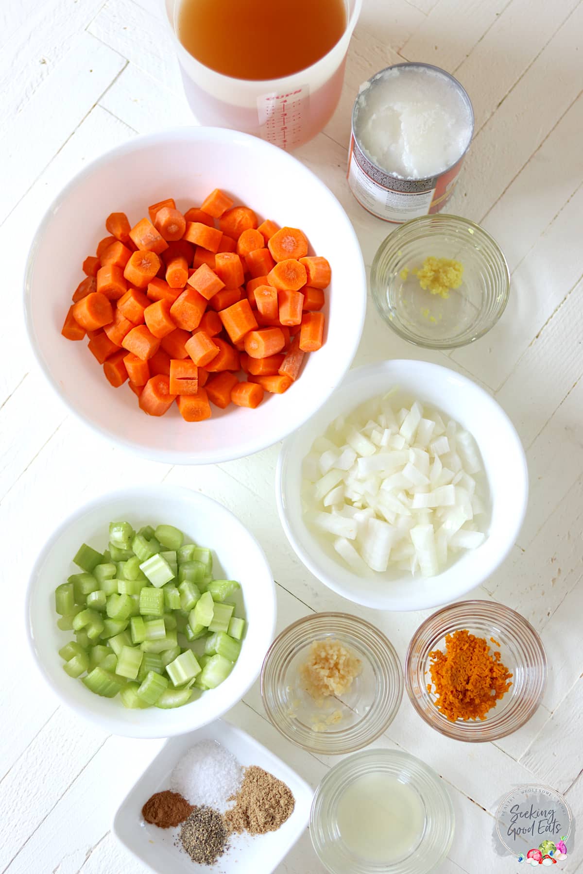 Ingredients needed for making carrot soup on a white board.