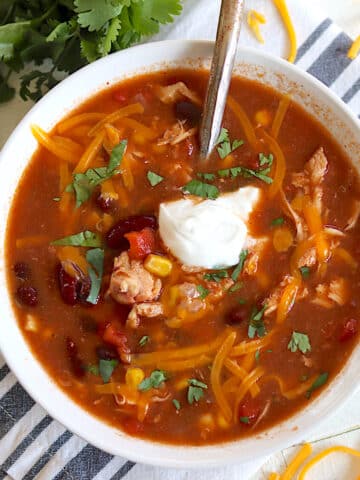 Slow cooker chicken taco soup served in a white bowl with cheese.
