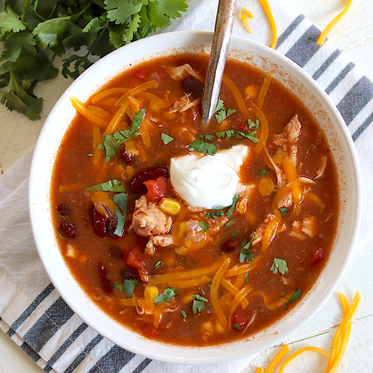 Slow cooker chicken taco soup served in a white bowl with cheese.