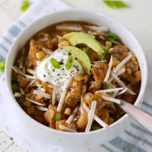 Slow cooker white chicken chili sitting on a blue and white stripe cloth napkin.