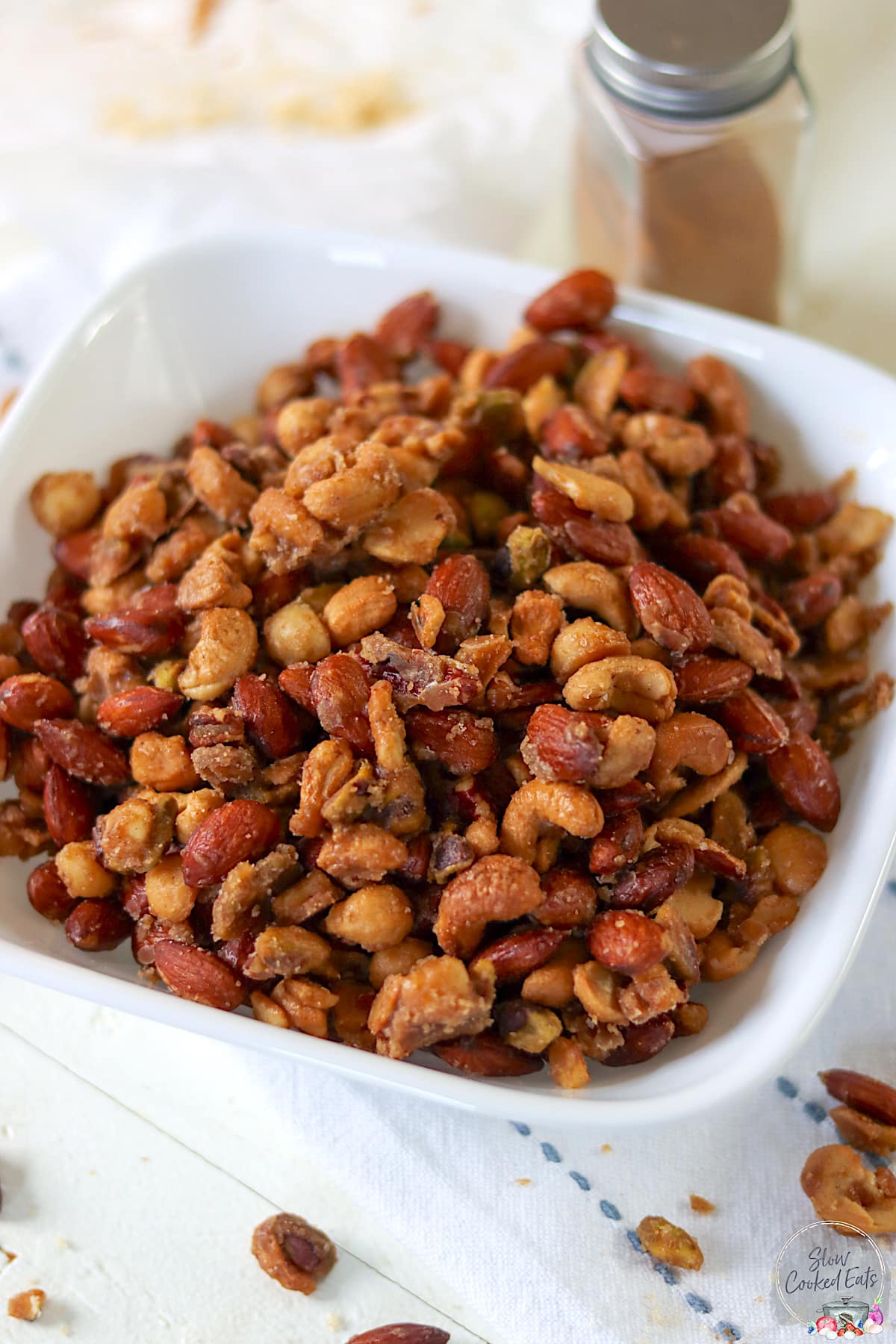 A square white bowl full of crockpot candied nuts.