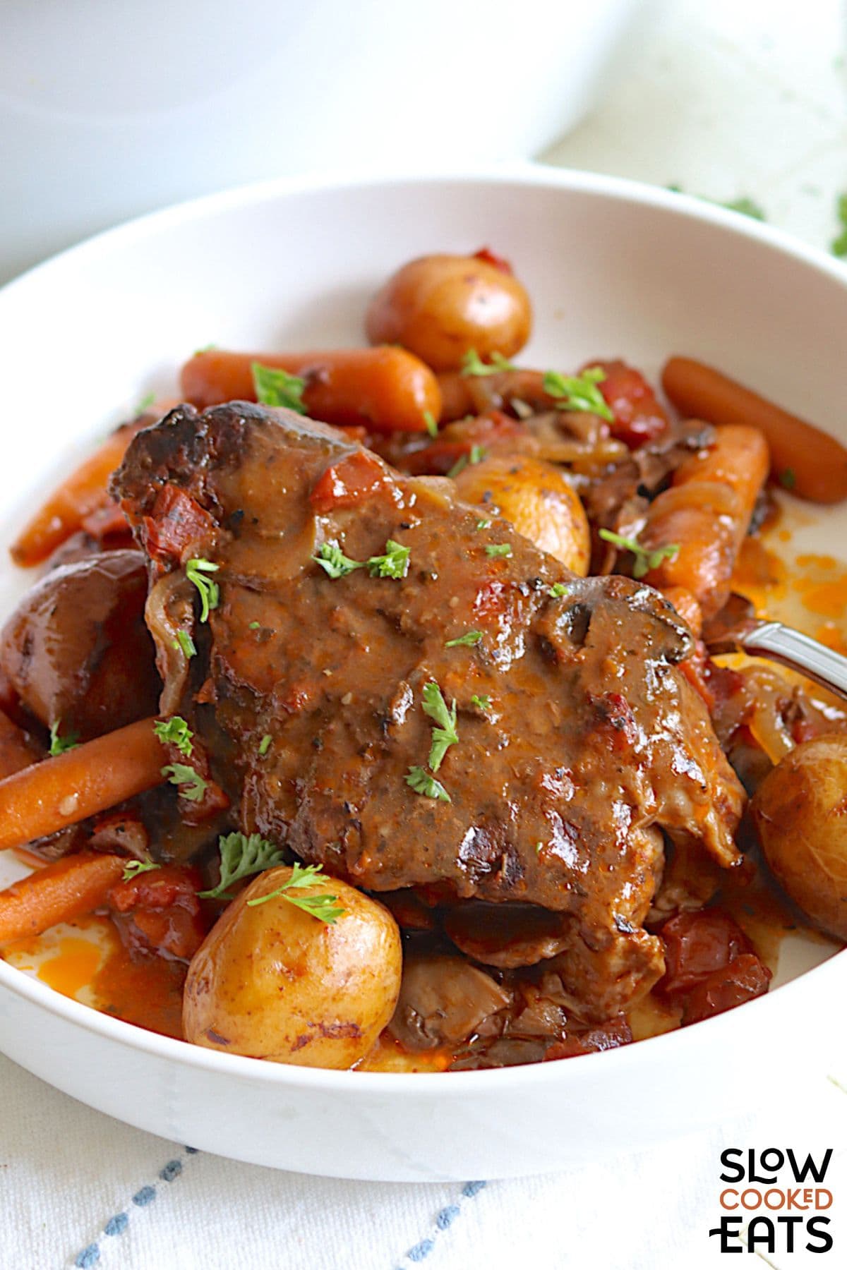Chuck roast and potatoes in crock pot being served in a white bowl.