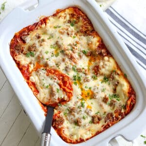 Crockpot lasagna served in a white rectangle slow cooker.