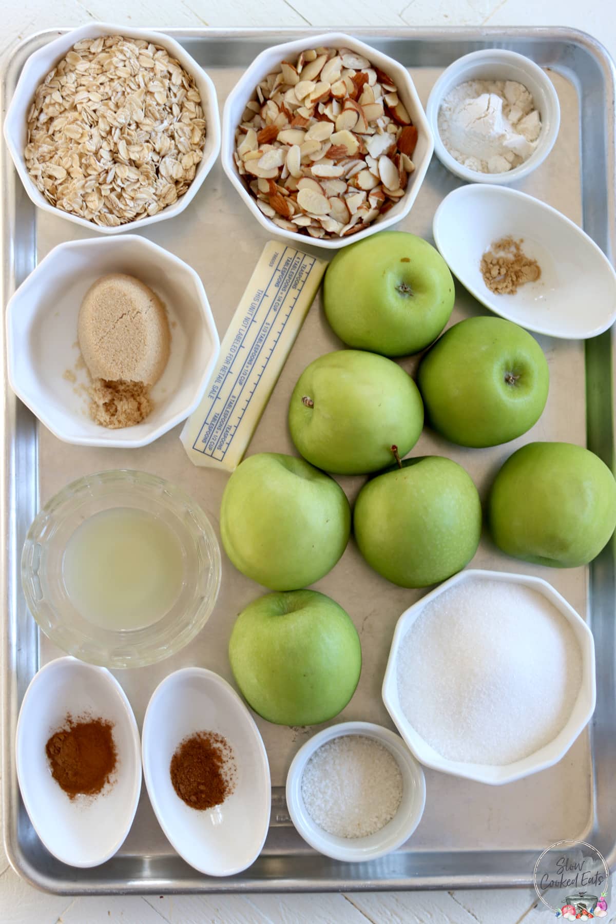 All the ingredients needed for making slow cooker apple crisp on a metal tray.