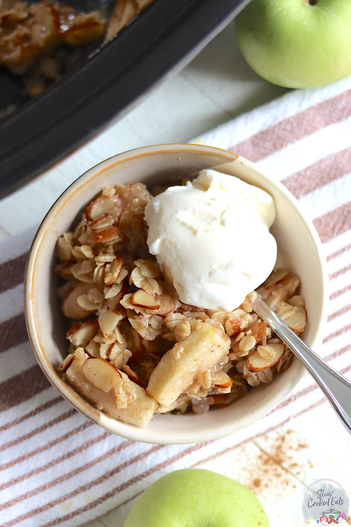 An off white bowl served with slow cooker apple crisp.