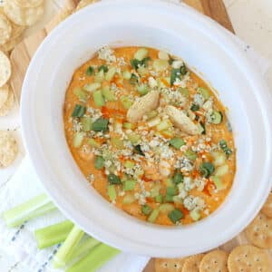 Hot slow cooker buffalo chicken dip in a white oval crock pot.