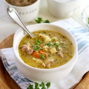A large white bowl of 5 ingredient crockpot chicken noodle soup with a spoon.