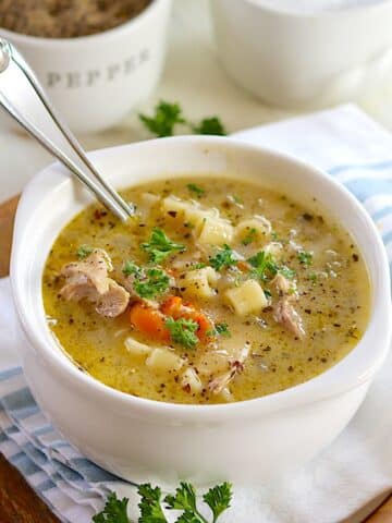 A large white bowl of 5 ingredient crockpot chicken noodle soup with a spoon.