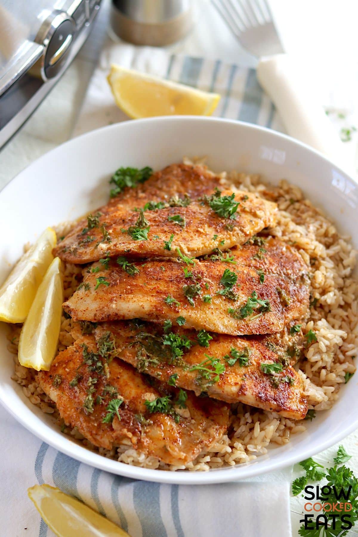 Serving of tilapia with lemon butter sauce on a white plate.