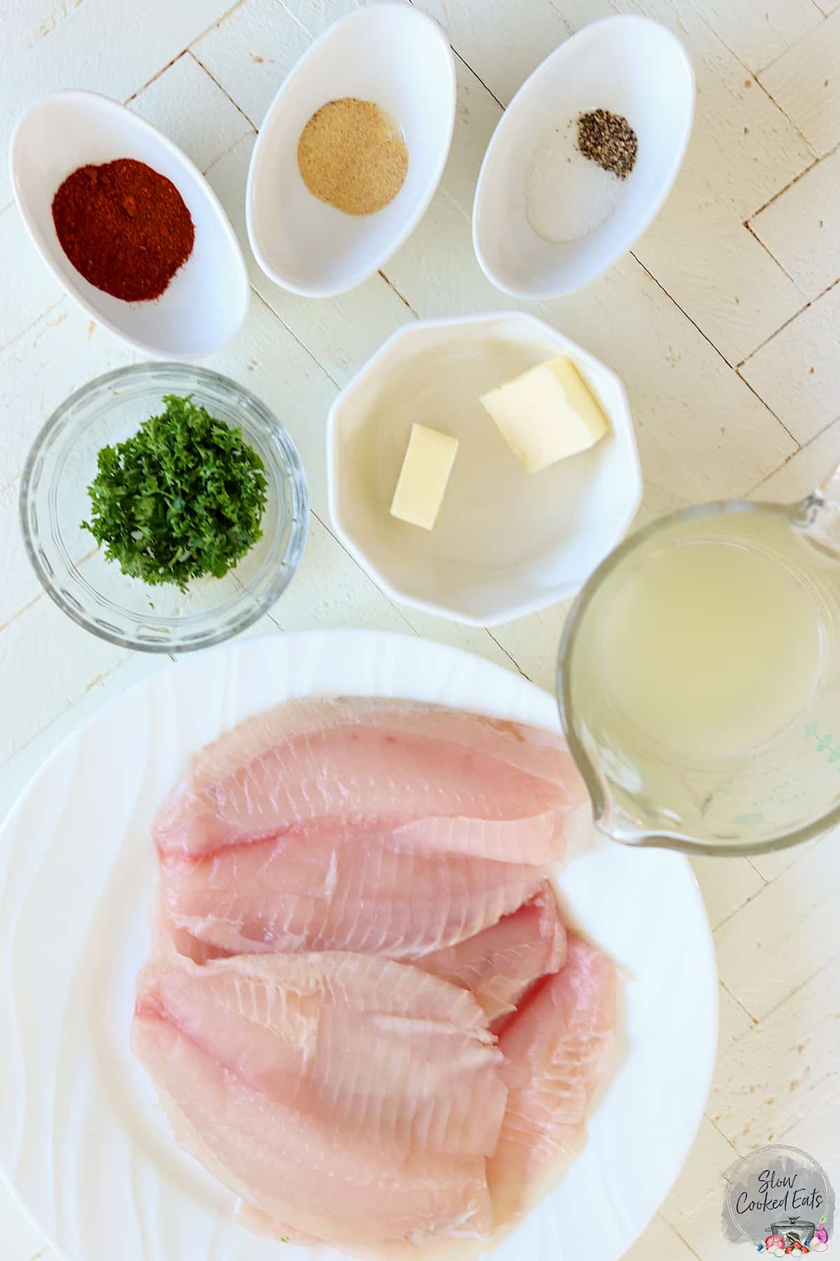 slow cooker tilapia ingredients on a wooded white board.
