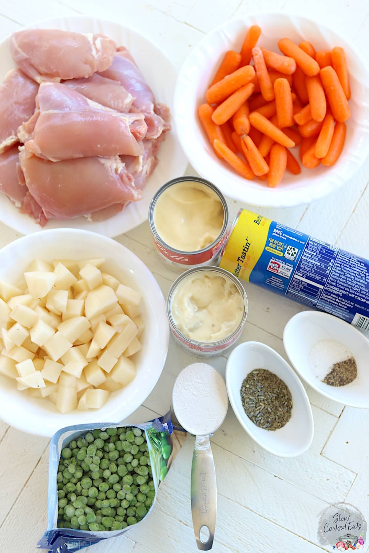 Ingredients needed to make slow cooker chicken and dumplings on a white wooded board.