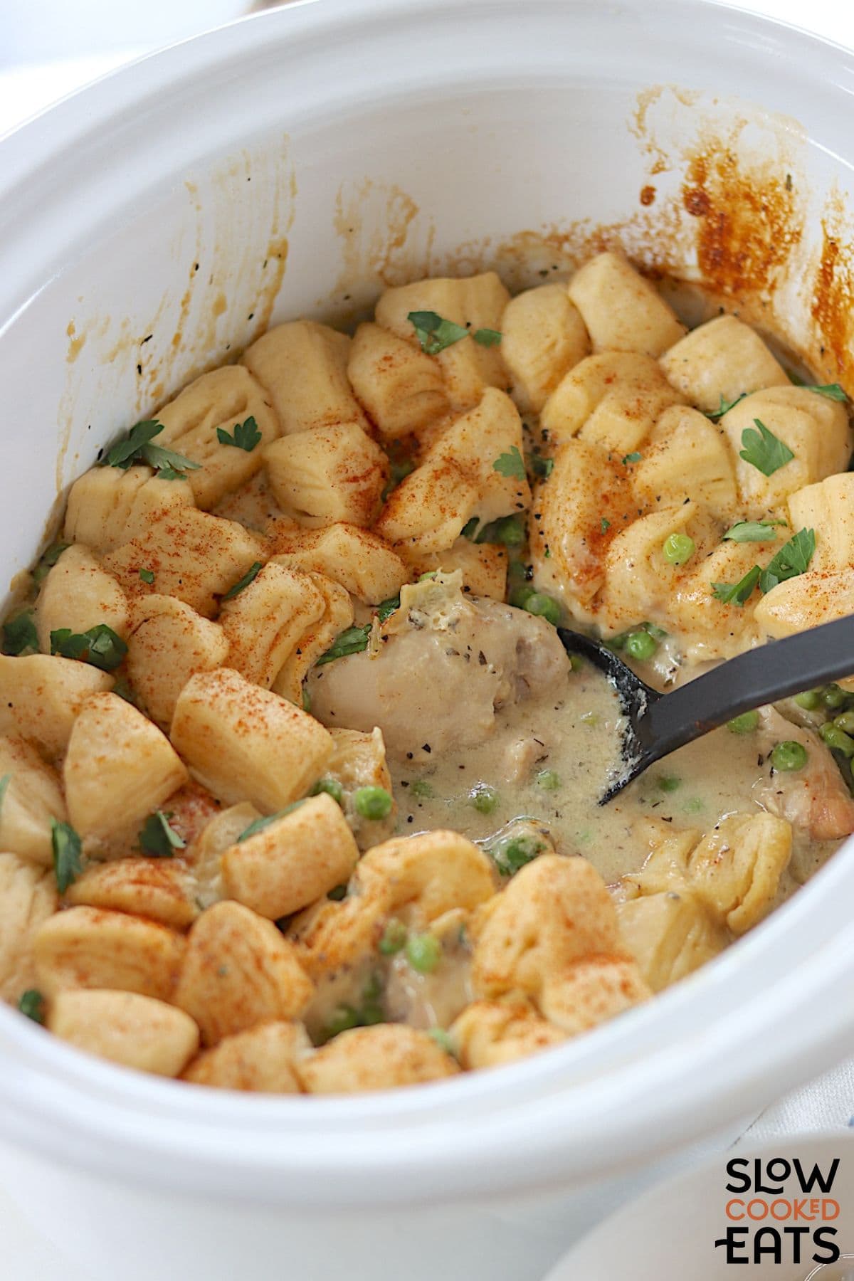Slow cooker chicken and dumplings with a serving spoon.