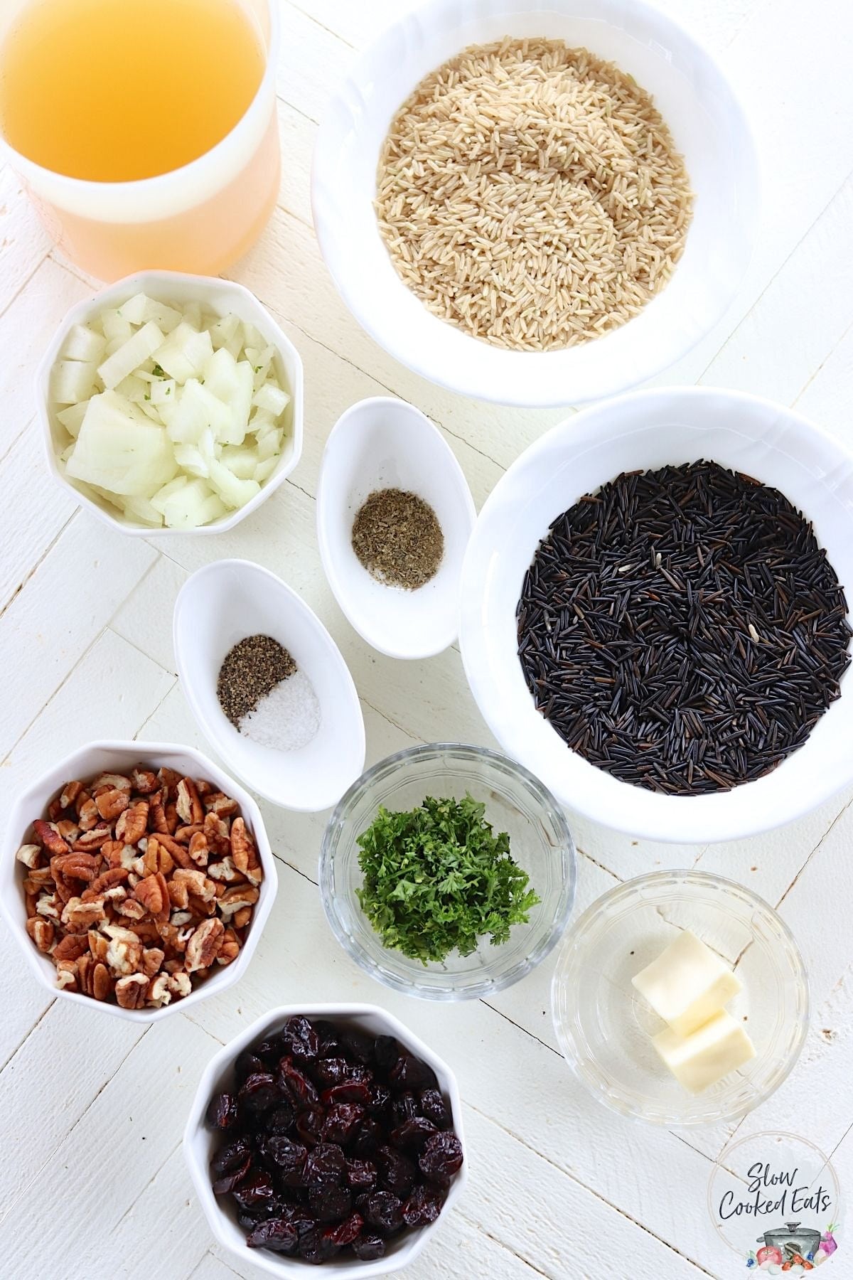Crockpot brown rice ingredients on a white wooden board.