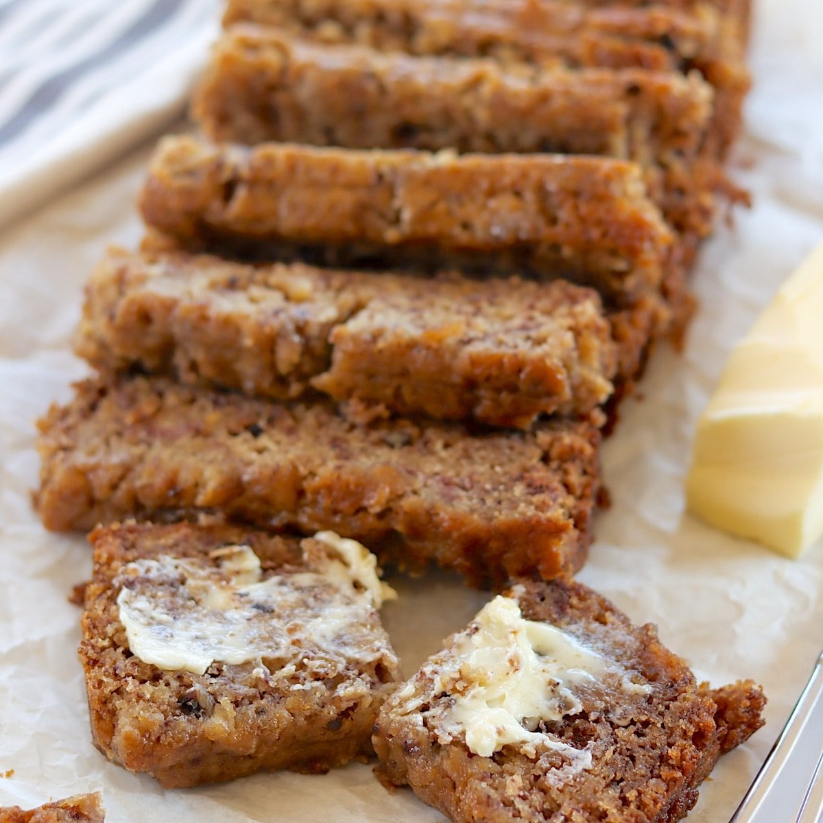Sliced and buttered crockpot banana bread on a white board.