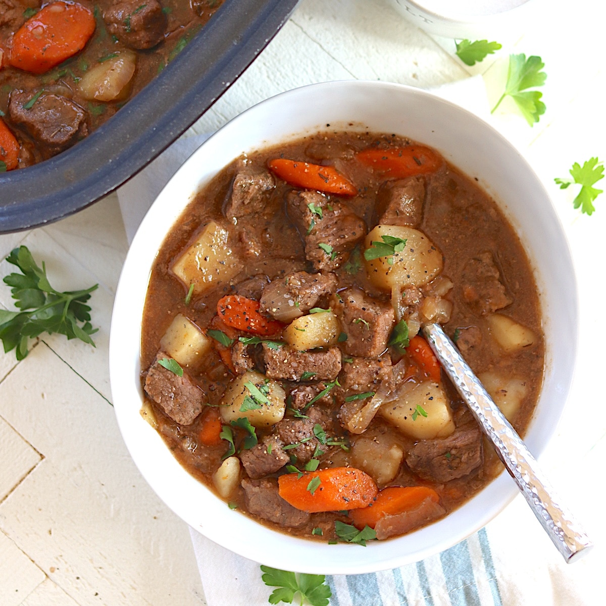 A white bowl served with crockpot irish stew garnished with fresh parsley.