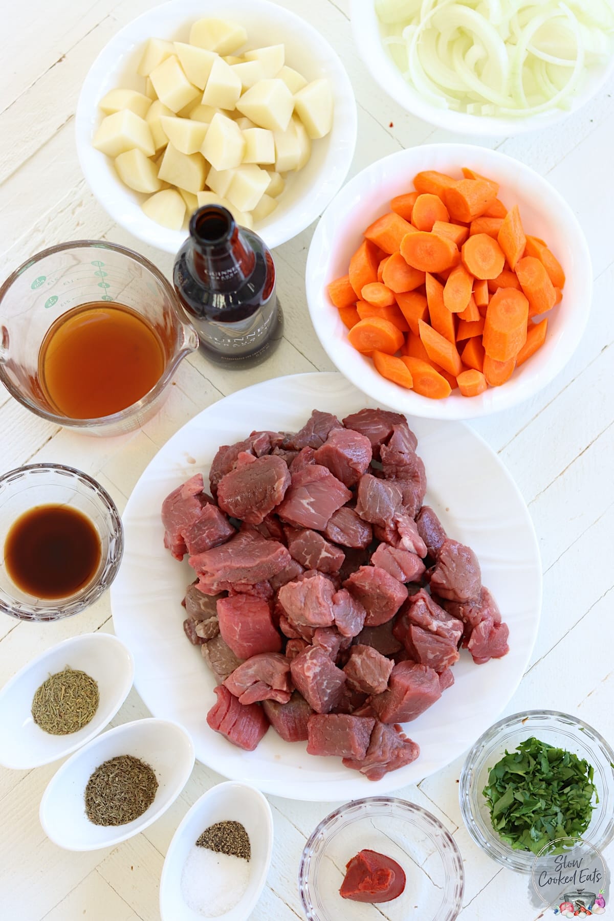 Ingredients for making slow cooker irish stew on a white wooden board.